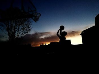 Low angle view of silhouette man playing basketball against sky during sunset