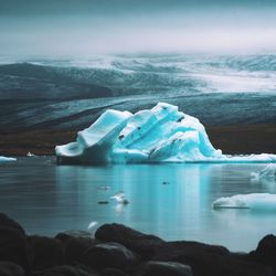 Ice floating on sea against sky during sunset