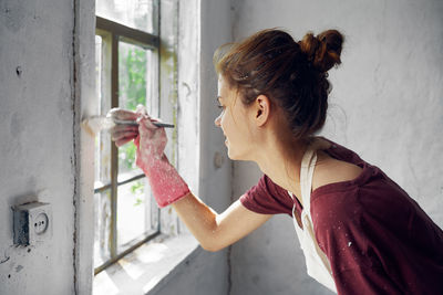 Side view of woman looking through window