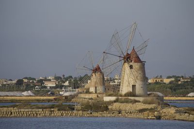 Sailboats in front of built structure against clear sky