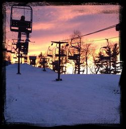 Snow covered bare trees against sky during sunset