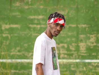 Portrait of young man standing against wall