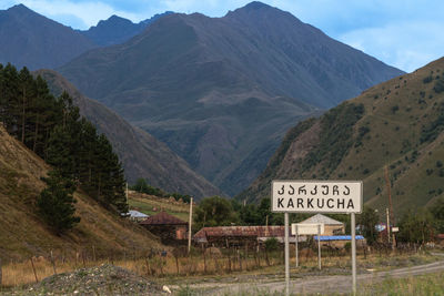 Road sign by mountains against sky