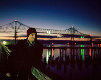 Man standing on bridge against clear sky at night