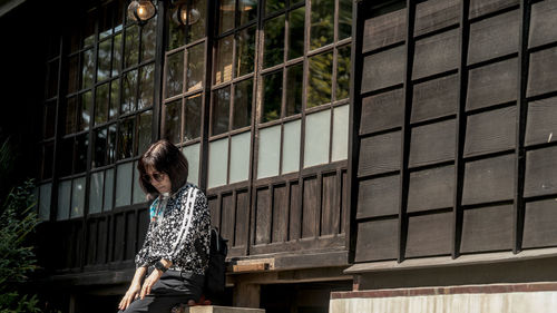 Woman standing by window of building