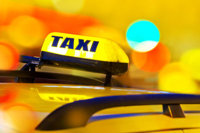 Close-up of illuminated yellow taxi text on car at night