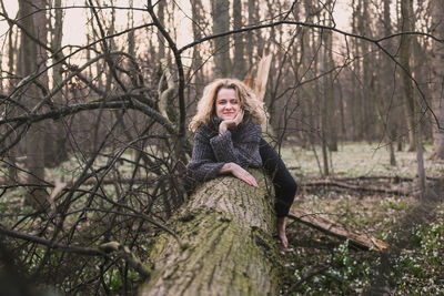 Positive lady resting on fallen tree scenic photography