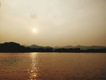 Scenic view of lake and mountains against sky at sunset