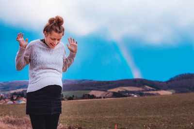 Happy pregnant woman gesturing while standing against blue sky