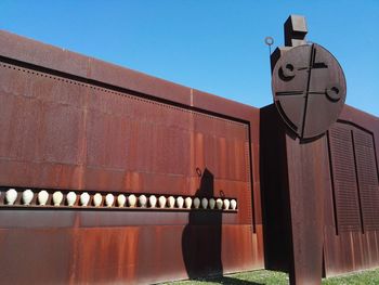 Low angle view of telephone pole against building against clear blue sky