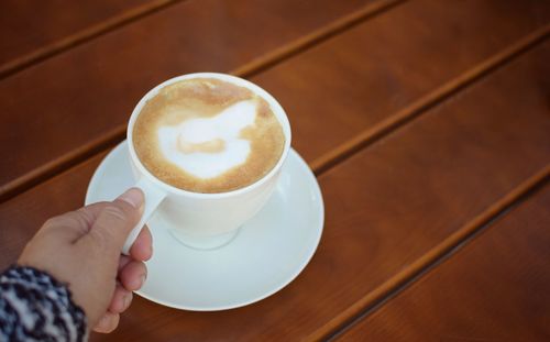 Midsection of person holding coffee cup on table