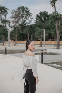 Portrait of woman standing against trees