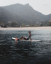 Man relaxing in lake against mountain range