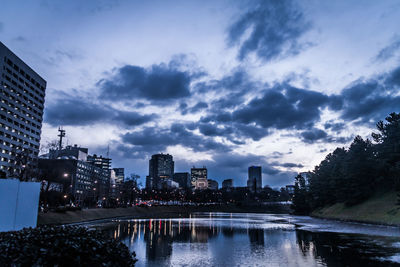 Lake and buildings against sky at dusk