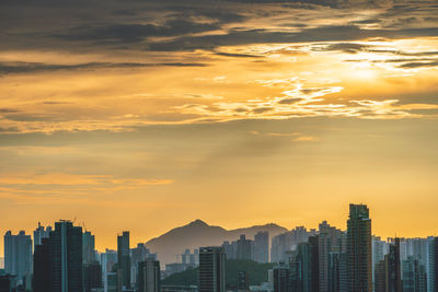 Modern buildings in city against sky during sunset