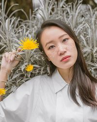 Portrait of young woman with sequins on face against plants