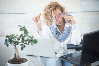 Young woman using phone while sitting on table