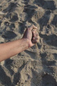 Close-up of hand on sand at beach