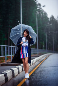 Full length of woman standing on wet road