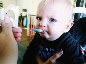 Close-up portrait of cute baby boy eating food at home