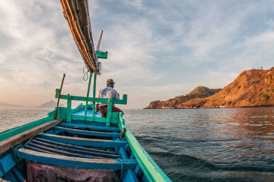 Man sitting on boat in sea against sky