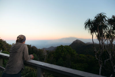 Side view of woman standing on mountain against sky