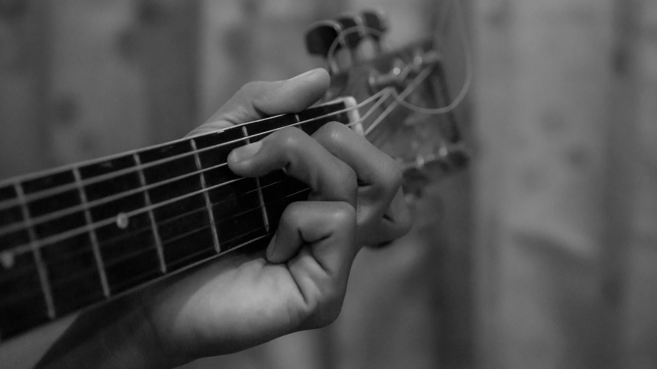 MIDSECTION OF MAN PLAYING GUITAR AT MUSIC CONCERT