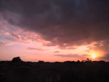 Silhouette landscape against dramatic sky during sunset