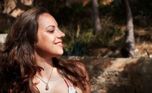 Close-up of smiling woman looking away in forest