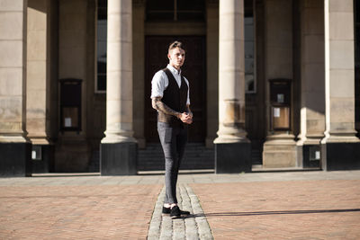 Fashionable man standing on footpath against building