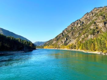 Scenic view of lake and mountains against clear blue sky