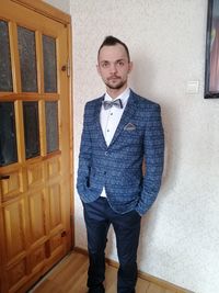 Portrait of young man standing against wall