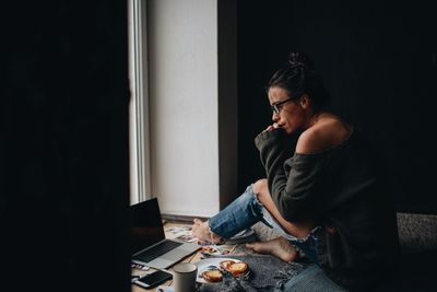 Young woman sitting on table at home