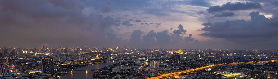 High angle view of illuminated cityscape against sky at dusk