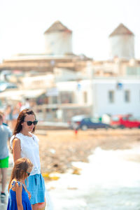 Side view of young woman standing against building