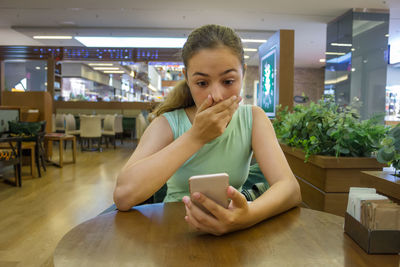 Portrait of young woman using mobile phone in restaurant