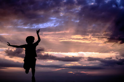 Silhouette man standing against dramatic sky during sunset