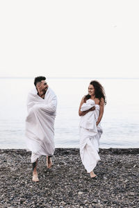 Young couple standing in sea against clear sky