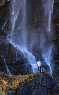 Rear view of man standing by waterfall