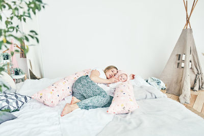Rear view of woman relaxing on bed at home