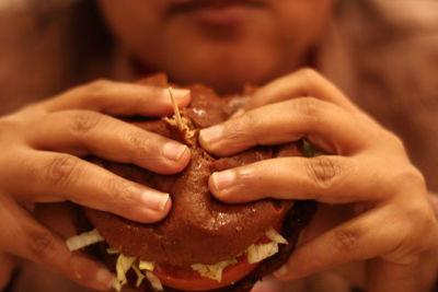 Cropped image of woman eating burger