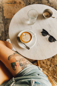 High angle low section of woman with coffee on table in cafe