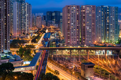 High angle view of illuminated city by buildings at night