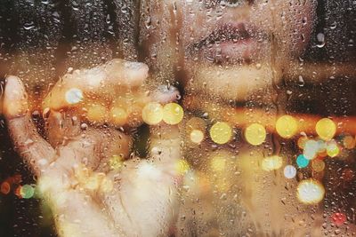 Close-up of woman seen from wet glass with reflection