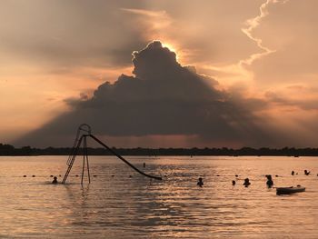 Silhouette boats in sea against sky during sunset