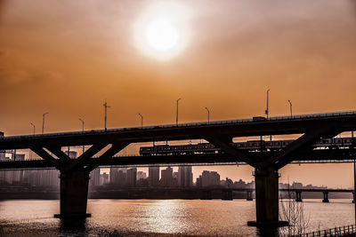 Bridge over river against sky during sunset