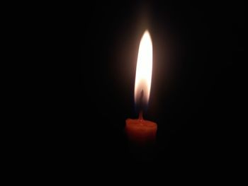 Close-up of illuminated candle in darkroom