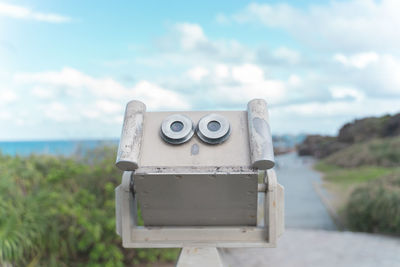 Close-up of machine part by sea against sky