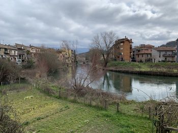 Buildings by river against sky