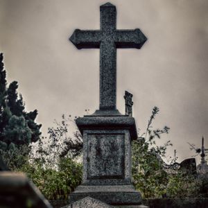 Cross in cemetery against sky